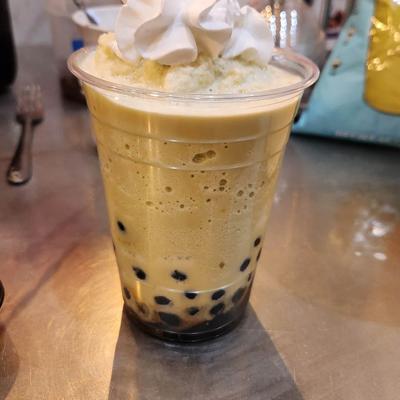 Bubble tea topped with whipped cream and mixed with tapioca pearls.