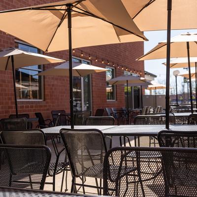 Patio seating beneath umbrellas and string lights.