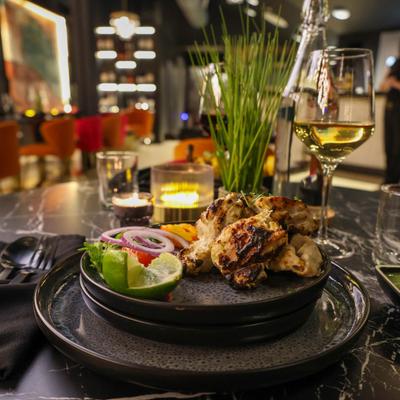 Tandoori chicken served with sides, alongside a glass of white wine.