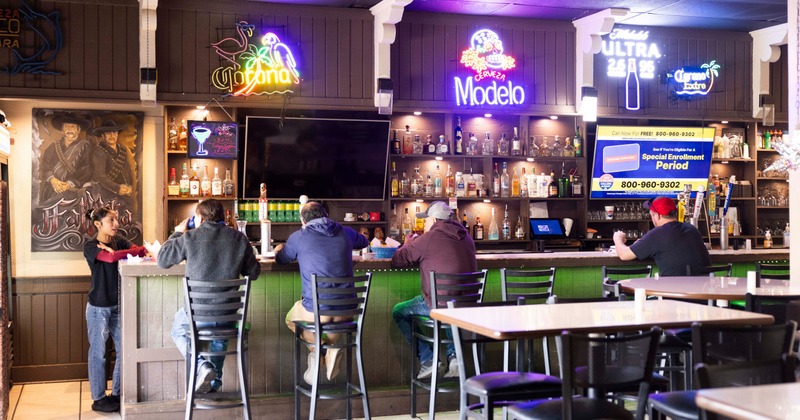 A bar with paintings and neon signs behind