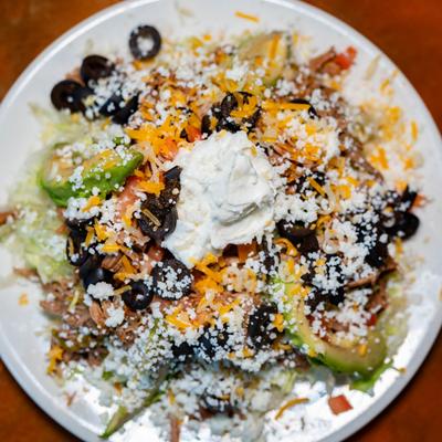 Deep fried tortilla, with beans, lettuce, tomato, cheese, olives, avocado, and sour cream.