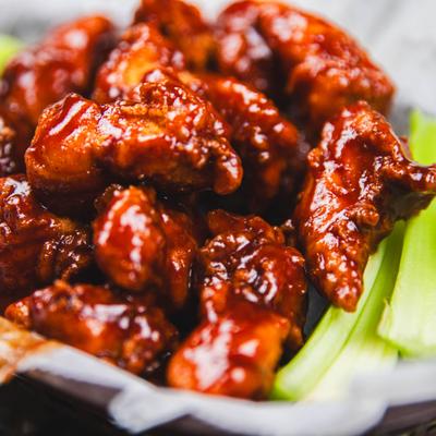 BBQ wings served with celery sticks, close-up.