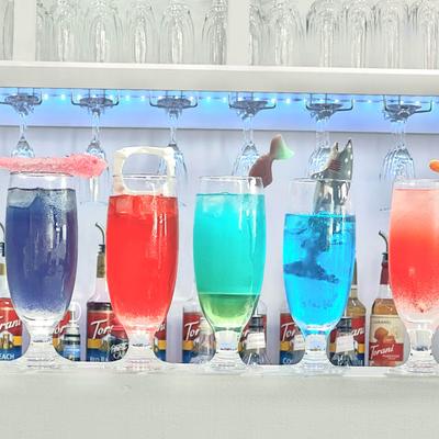 Assorted colorful Mimosas with garnishes,  neatly arranged on a bar counter.
