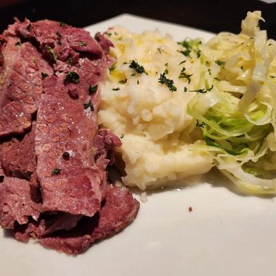 A plate of corned beef with mashed potatoes and shredded cabbage.