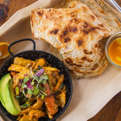Roti served with wok veggies and chicken, and a side avocado.