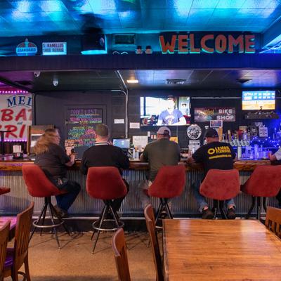 Interior with tables, chairs, and guests seated at the bar.