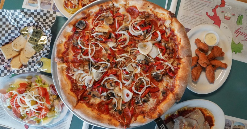 Overhead view of a pizza topped with pepperoni, mushrooms, and onions
