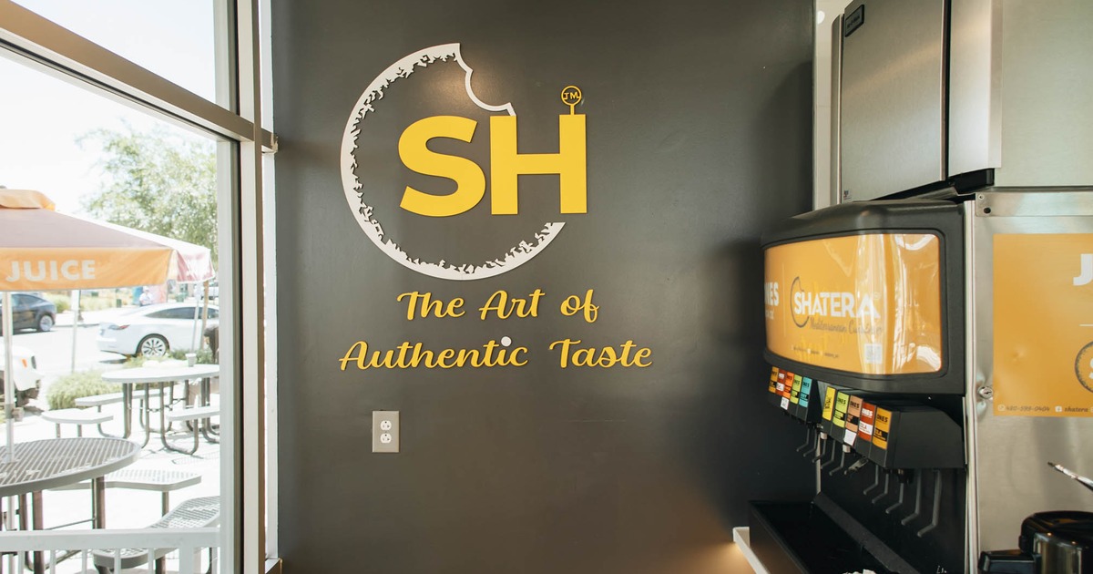 Restaurant sign set within a circular design on a dark wall, beside a beverage fountain machine