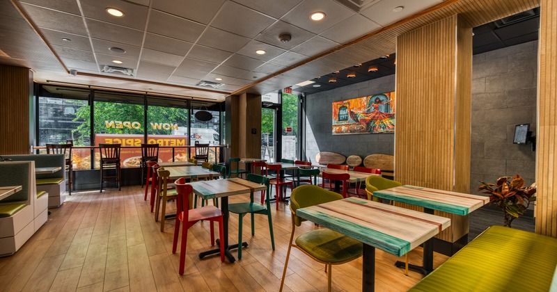 A modern restaurant interior with wooden tables and colorful chairs