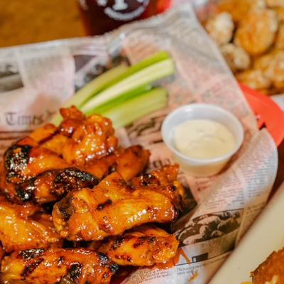 Wings coated in sauce, served with celery sticks and a dipping sauce.