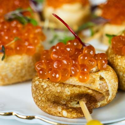 Red Caviar Appetizer featuring salmon roe served on small pieces of bread.