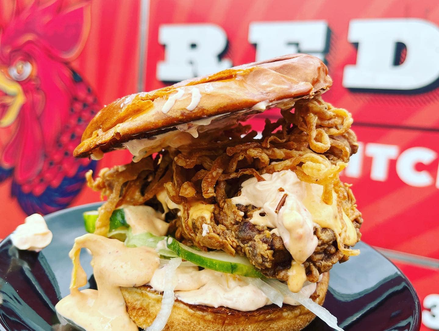 Fried chicken sandwich, with spicy aioli, cucumber, and crispy onion strings