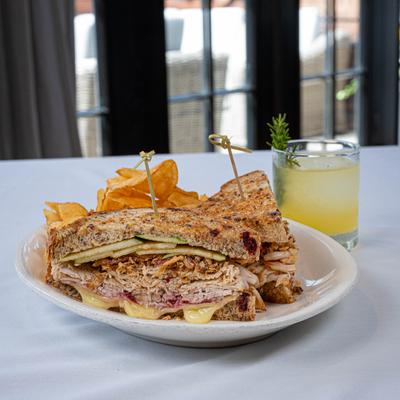 Sandwich - turkey, cheese, apple slices, chips; a glass of lemonade.