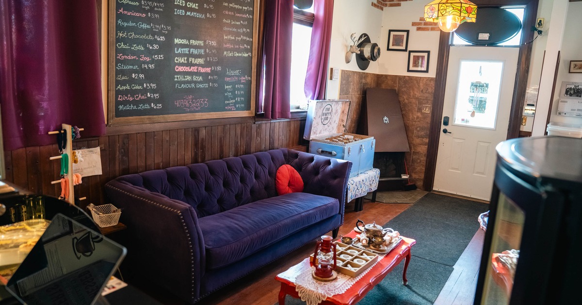 Cozy café interior with a purple sofa, red coffee table, and a large menu board