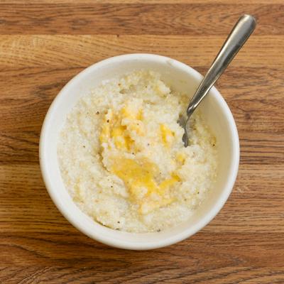 Bowl of grits with a spoon in it, top view.