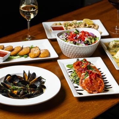 Assorted Italian dishes served on table with a glass of wine.