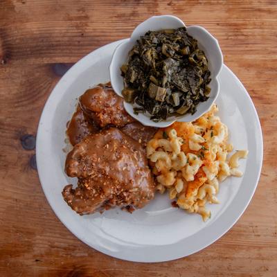 Smothered pork chops with mac and cheese and collard greens.