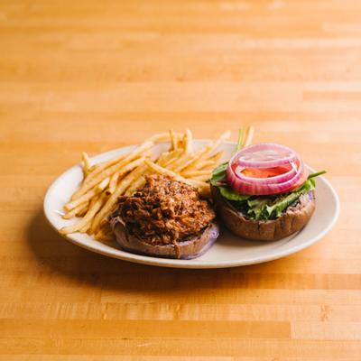Pulled pork sandwich served with French fries.
