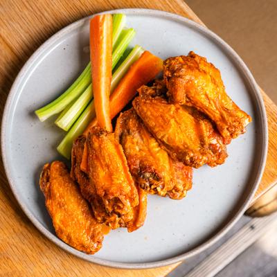 Chicken wings served with celery and carrot sticks.
