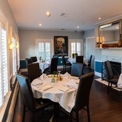 Indoor seating with round tables covered in white tablecloths and leather chairs.