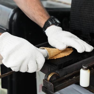 An employee skillfully rolling an ice cream cone.