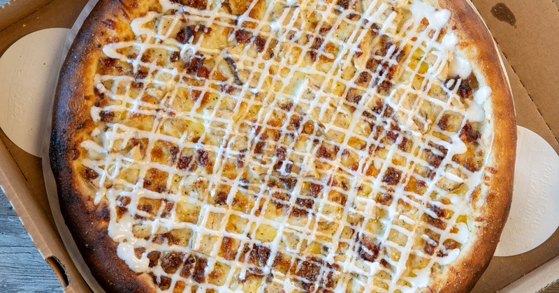 Pizza with shredded mozzarella, grilled chicken, bacon, nad ranch drizzle