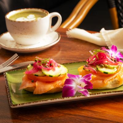 A plate of lox bagel and a cup of latte on a wooden table.
