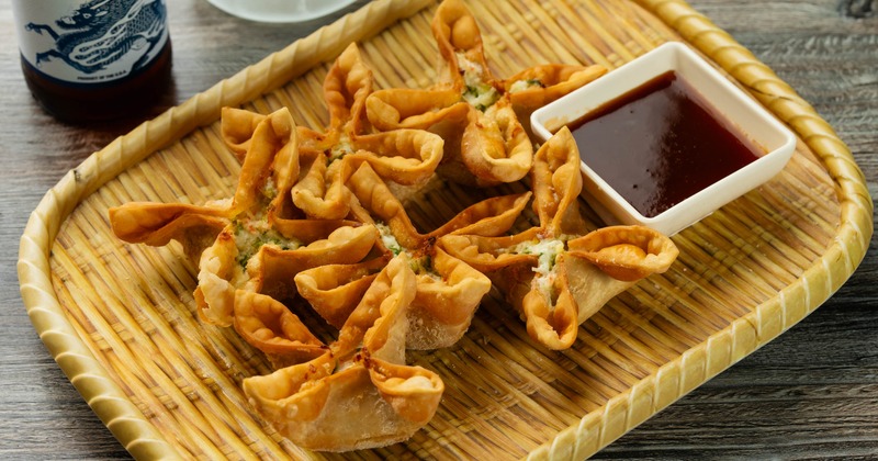 Crab rangoon dumplings served with a dipping sauce