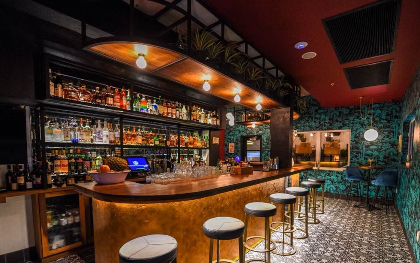 Bar area with a counter, stools, overhead lights and drink shelves behind the bar