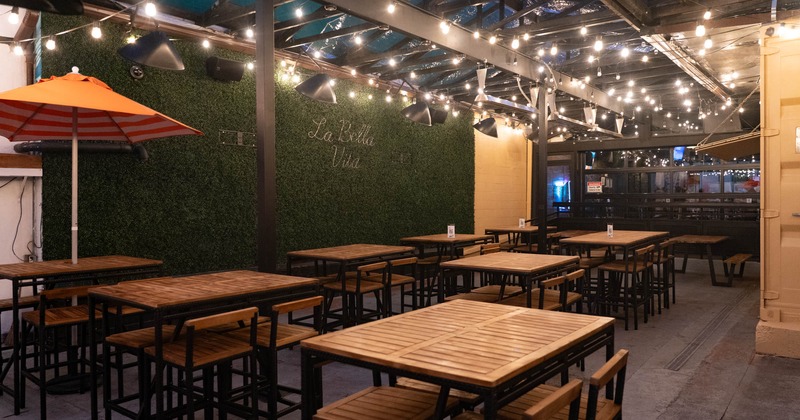 Exterior, high seating tables and chairs, large artificial green wall with neon signage