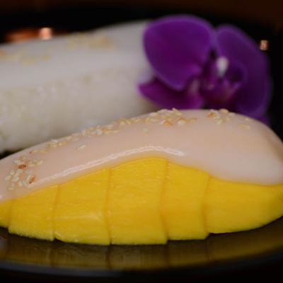 Mango sticky rice om a plate decorated with a purple orchid flower.