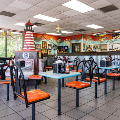 A casual seafood restaurant interior featuring a decorative lighthouse and bright orange chairs.