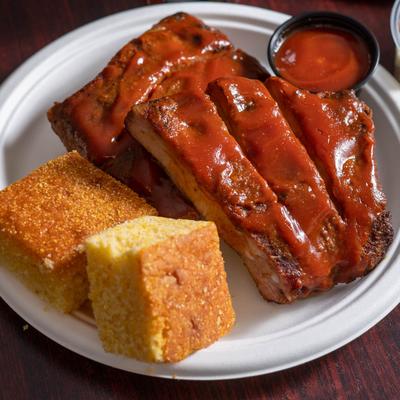 Half rack of ribs with a sauce and cornbread.