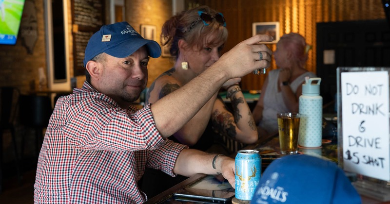 Interior, high seating area by the window, tables with stools, brick walls, TV on the wall