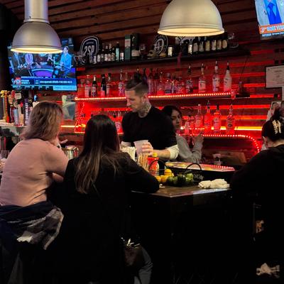 Bartender preparing drinks behind the bar with people seated at the counter.