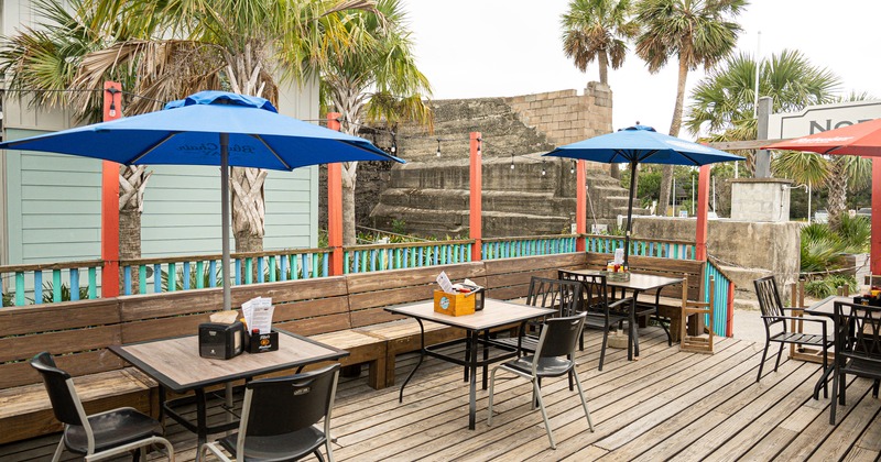 Exterior, seating area, tables, chairs, benches, parasols, tropical trees, stone building