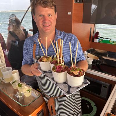 A food truck employee holding a tray with poke bowls on it.