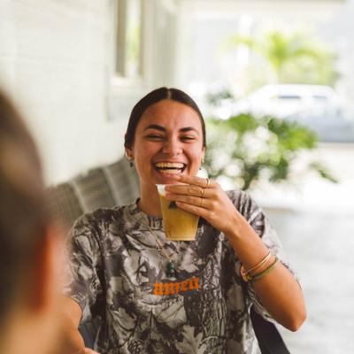 Laughing guest holding an iced drink while sitting at an outdoor table.
