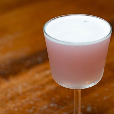 Light pink cocktail with creamy foam in a stemmed glass.
