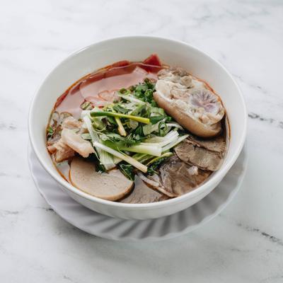 Spicy beef bone noodle soup with herbs and vegetables.