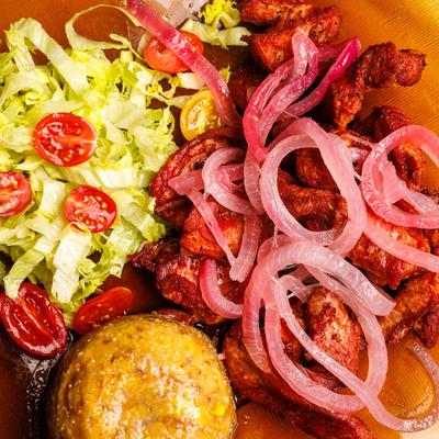 Fried pork belly chunks with rice, pickled onions, lettuce, and cherry tomatoes.