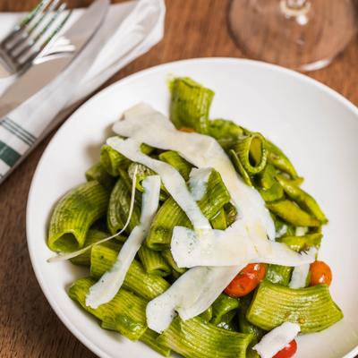 Rigatoni pasta in pesto sauce, with shaved parmesan and tomatoes.