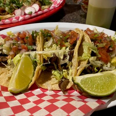 Tacos with meat, lettuce, and salsa on a checkered plate.