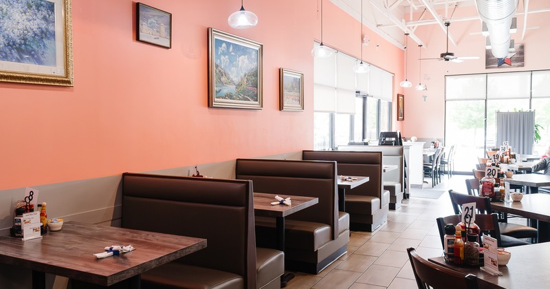 Cozy dining area with upholstered dining booths along the wall and tables and chairs