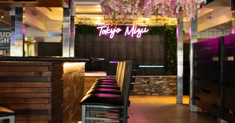 Interior, a bar area with high-top chairs, wood paneling, and the Tokyo Mizu neon sign
