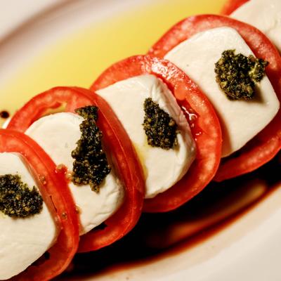 Caprese Salad with tomato slices, mozzarela and basil pesto, close-up.