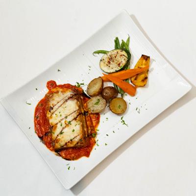 Eggplant Parmigiana served with cooked vegetables, top view.