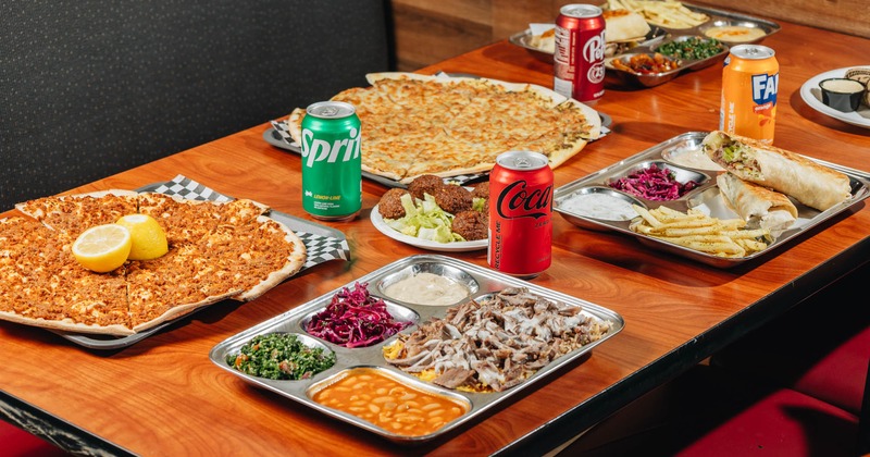 Assorted food plates arranged on a table with canned soft drinks