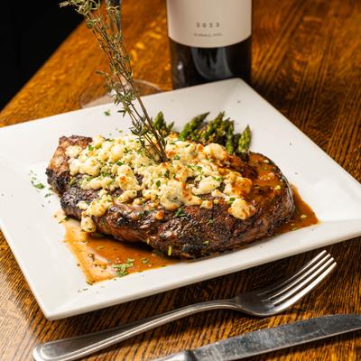 Grilled steak with blue cheese, asparagus, and thyme garnish.