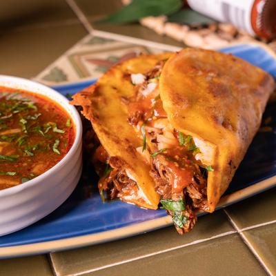 Quesabirria tacos, served with birria sauce.